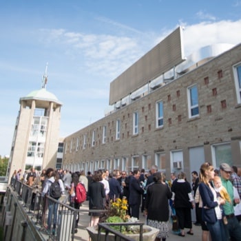 A large group of people mingling on an outdoor patio on the Tyndale campus