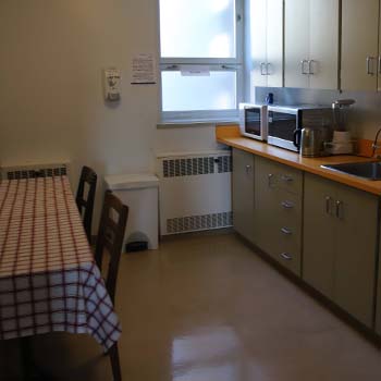 A shared common kitchenette with a large dining table, counterspace, sink and microwave