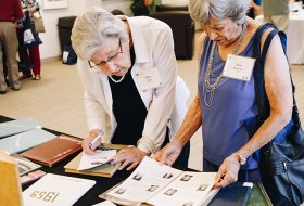Two alumni ladies looking at yearbooks