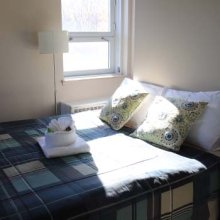 Single Bed with pillows with bright lights shedding through near the bed-side window