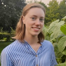 a headshot of Nicole standing in front of a bush with large leaves