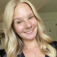 Maddie standing in front of a background with some pictures and a door.